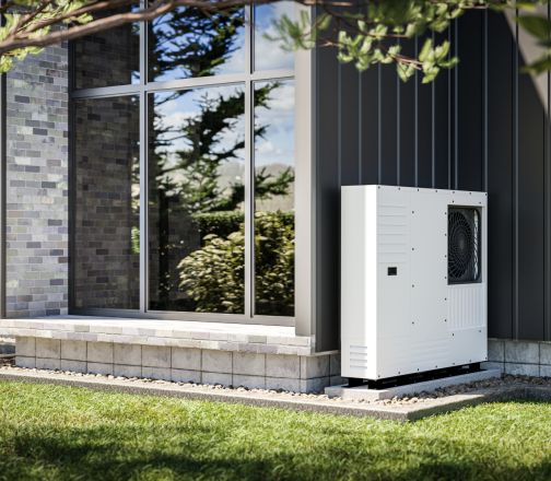 An der Wand eines Einfamilienhauses installierte Wärmepumpe mit erneuerbaren Energiequellen